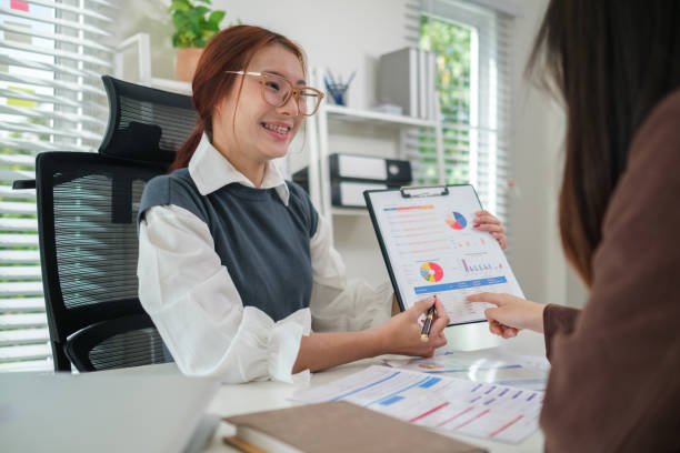 Asian businesswoman and colleague reviewing a business plan together in a professional setting.
