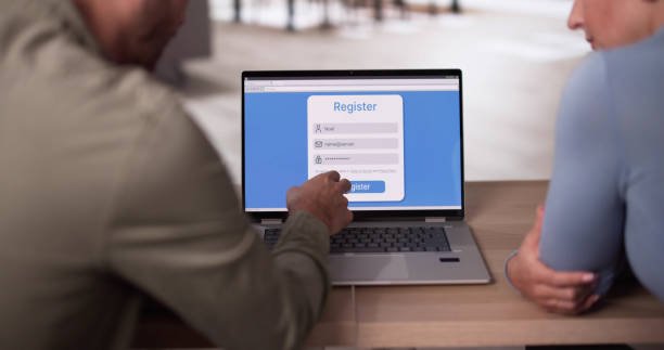 Two people seated at a table, working on a laptop and using a phone, focused on reviewing and correct online credit report errors.